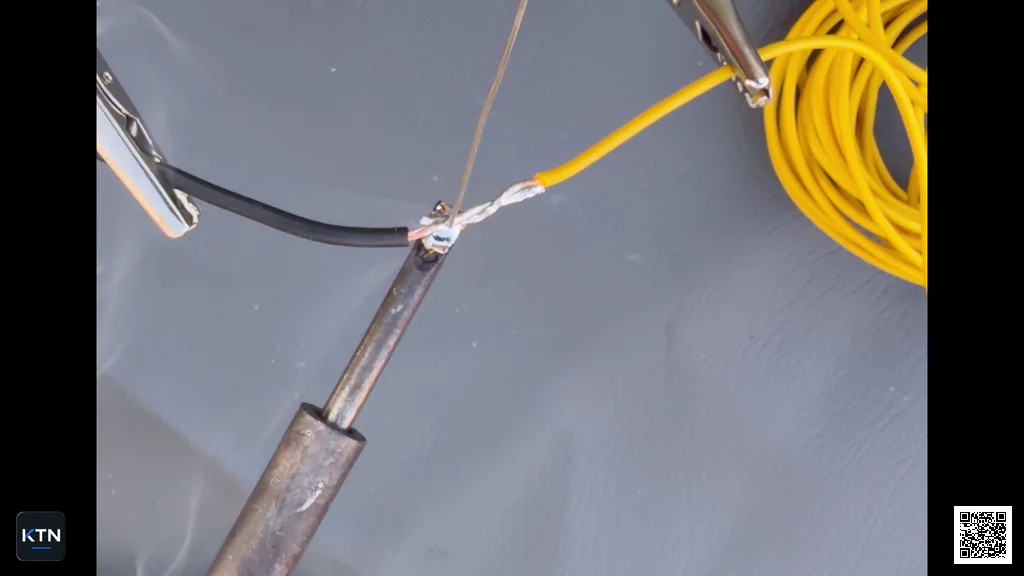 Solder being fed from above while the wire splice is heated from below with the soldering iron