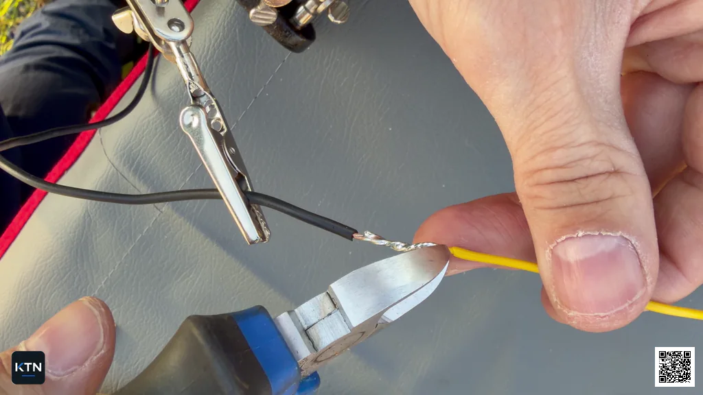 Side cutters trimming a sharp copper strand from the soldered wire splice