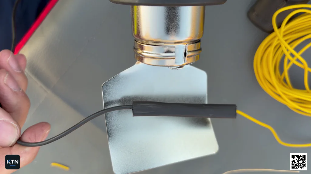 Heat gun evenly shrinking black heat-shrink tubing around the wire splice